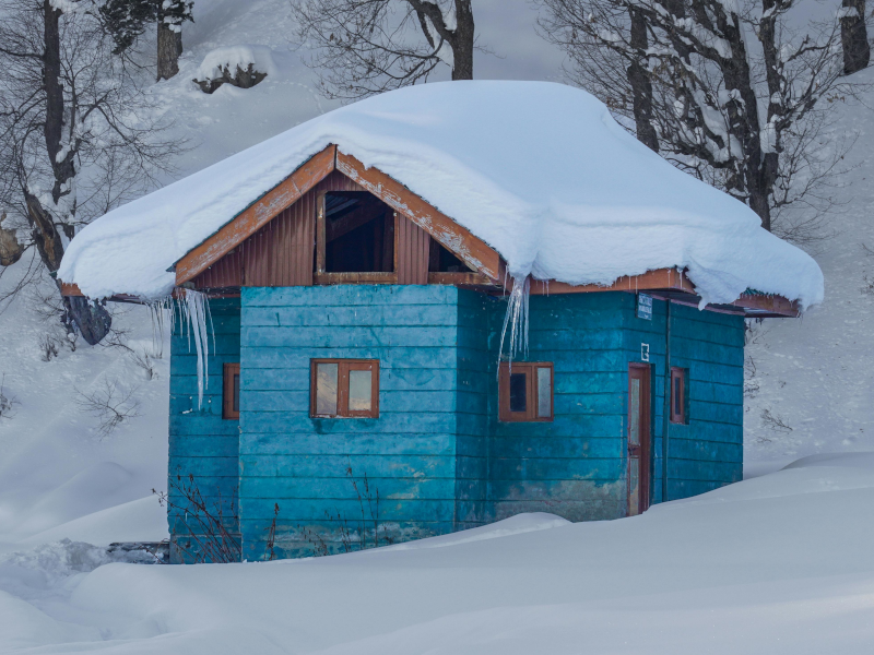 Image: A photo showing a deep, multi-layered snowpack on a cabin roof in the B.C. interior, illustrating the immense weight.